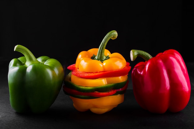 Tres pimientos sobre un fondo de madera, cocinar ensalada de verduras