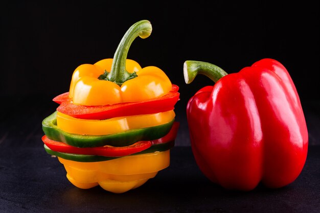 Tres pimientos sobre un fondo de madera, cocinar ensalada de verduras