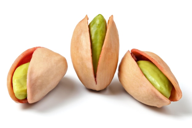 Tres pistachos rojos turcos (Antep Fistigi) nueces verdes peladas visibles bajo la cáscara, aisladas sobre fondo blanco.