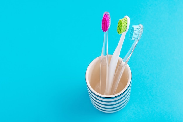 Tres plásticos coloridos cepillos de dientes en vidrio sobre un fondo azul, de cerca