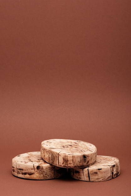 Tres plataformas aserradas redondas verticales o podio de madera para la presentación de cosméticos de belleza ecológicos en el espacio de copia de fondo marrón