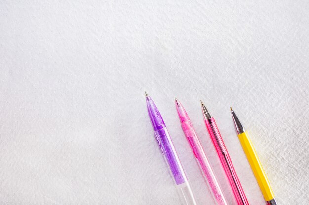 Tres plumas aisladas en blanco. Bolígrafos de color rosa, violeta y amarillo.