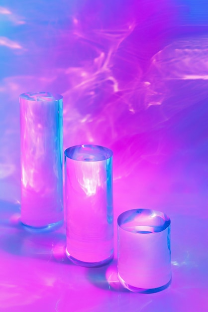 Tres podios de cilindro de vidrio claro sobre un fondo rosado pastel