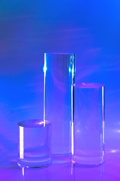 Tres podios de cilindro de vidrio transparente sobre un fondo de neón holográfico