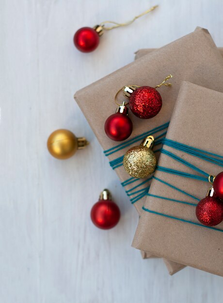 Três presentes embrulhados em papel ofício com bolas vermelhas e douradas de Natal