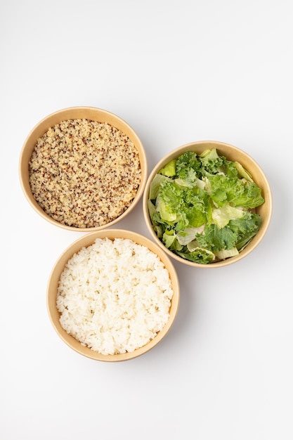 Três puxões com arroz de quinoa e salada verde em fundo branco