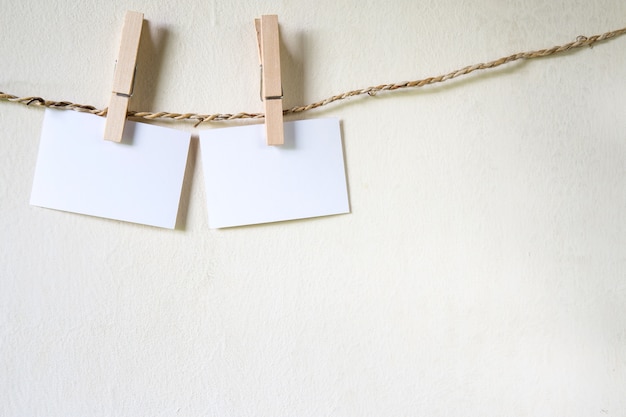 Foto três quadrados de papel em branco, atrelados a uma linha de lavagem de cordas