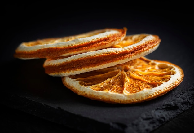 Tres rodajas redondas de naranja seca sobre un fondo negro