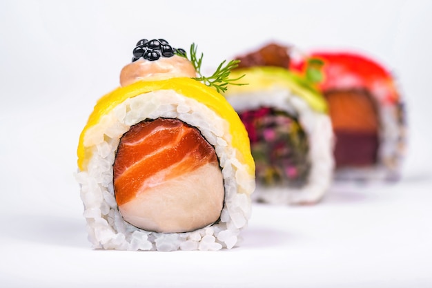 Tres rollos de sushi con salmón, aguacate, atún y pepino aislado en blanco