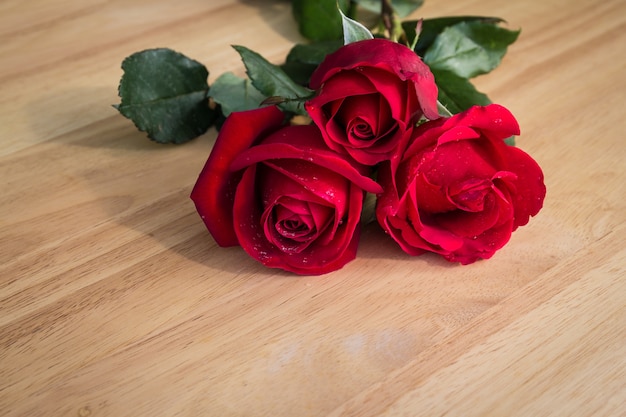 Tres rosas rojas sobre fondo de madera