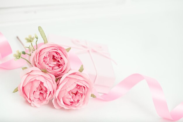 Tres rosas rosadas con cinta y caja de regalo en la mesa blanca Concepto del día de San Valentín