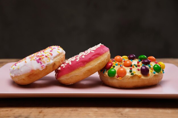 Três rosquinhas apetitosas estão em um prato de cerâmica rosa.