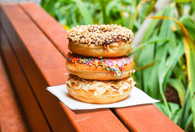 Três rosquinhas em um prato de papel, uma com nozes e outra polvilhada.