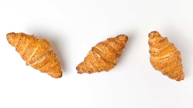 Tres sabrosos croissants sobre fondo blanco comida francesa plana