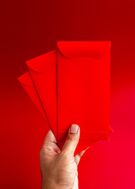 Tres sobres rojos sostenidos a mano aislados sobre fondo rojo estilo vertical 3 paquetes Hongbao para regalo de dinero de la suerte en el año nuevo lunar chino en el mes de enero boda paquete rojo