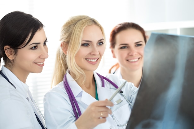 Três sorrindo médica médica olhando para a imagem de raio-x. conceito de cuidados de saúde e medicina.