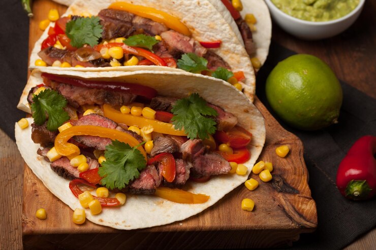 Foto três tacos mexicanos com carne de vaca de mármore, angus preto e vegetais numa velha mesa rústica.