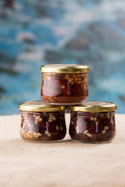 Tres tarros de mermelada con fresas y piñones.