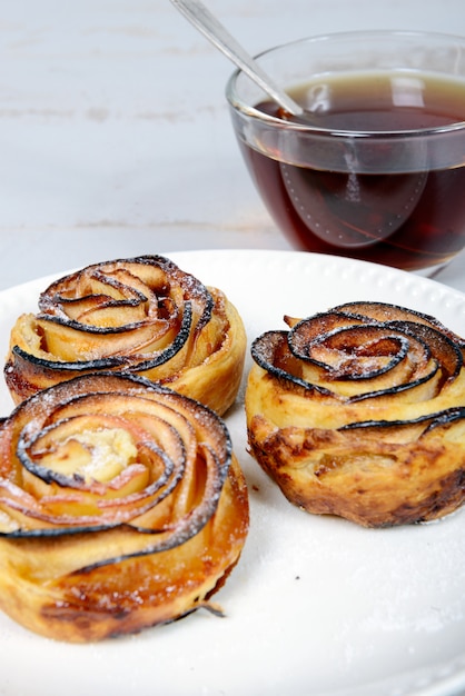 Tres tartaletas de manzana en plato y taza de té