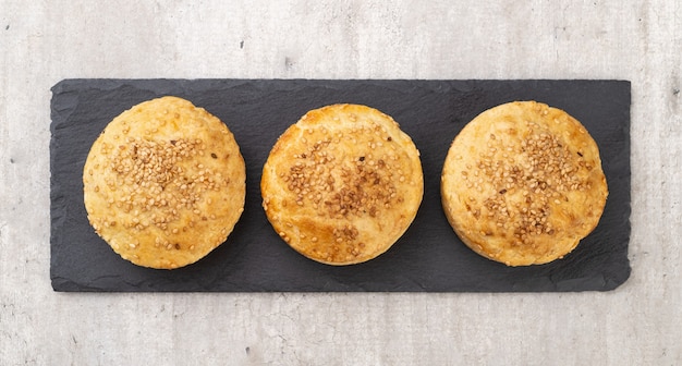 Tres tartas caseras rellenas de sésamo sobre tablero de piedra.