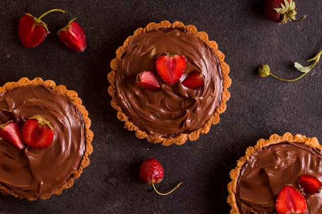 Tres tartas con frutos rojos sobre fondo negro. vista desde arriba