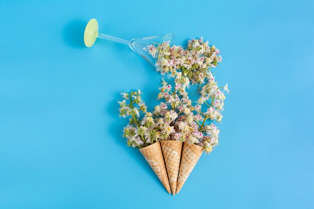 Tres tazas de oblea crujientes dulces con flores de castaño sobre un fondo azul Los pétalos de castaño se vierten de una copa de martini