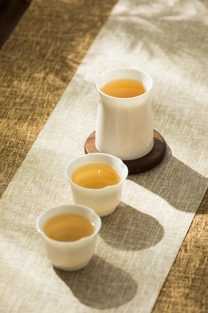 Tres tazas de té verde se sientan en una mesa junto a una taza blanca Perfiles de sabor de té por técnica de preparación