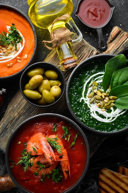 Tres tazones con sopa de colores Sopa de zanahoria, tomate y espinacas Comida saludable Sobre un fondo oscuro