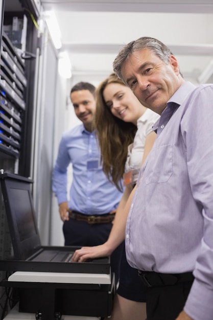 Tres técnicos felices que controlan los servidores con la computadora portátil