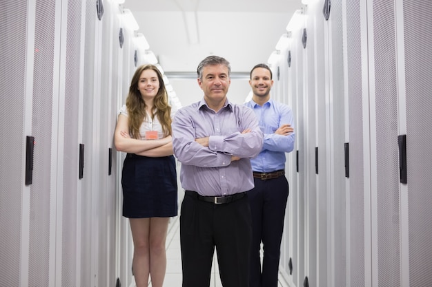 Tres técnicos sonrientes que se colocan en centro de datos