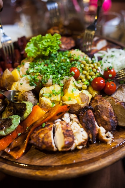 Tres tipos de carne con lechuga y tomate sobre una tabla de madera