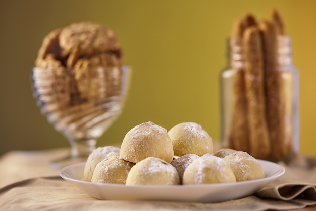 Três tipos de biscoitos em tons de bege em um guardanapo em um prato e em uma jarra. O conceito de estilo rústico