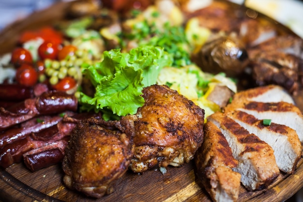 Três tipos de carne com alface e tomate em uma placa de madeira