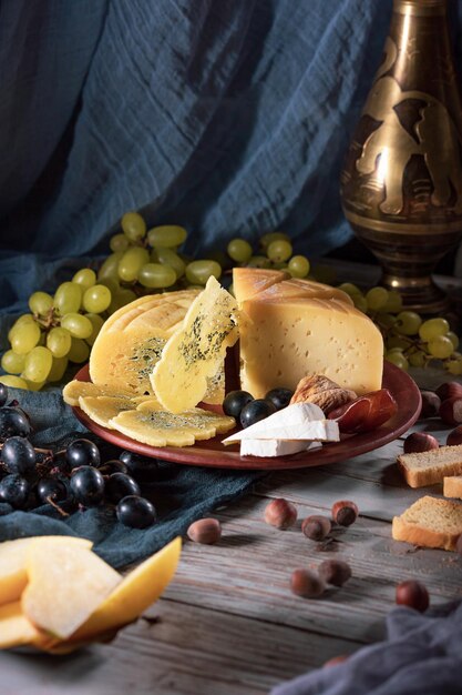 Três tipos de queijo em um prato uvas vermelhas e verdes figos tâmaras nozes e pão comida deliciosa e saudável foto ertical