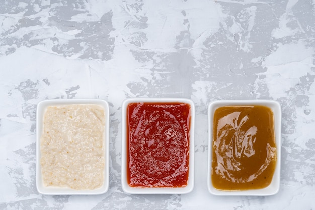 Tres tipos de salsas sobre un fondo de cemento blanco