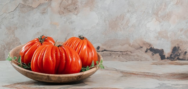 Três tomates e orégano frescos de Raf Coeur De Boeuf em um fundo marrom