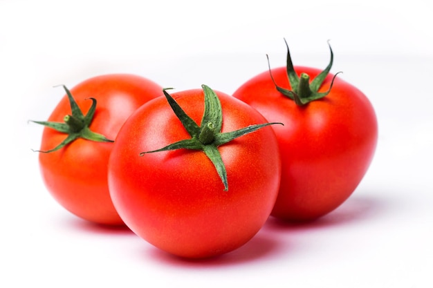 Tres tomates rojos maduros sobre fondo blanco aislado, de cerca