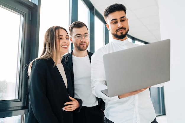 Tres trabajadores de oficina mirando portátil