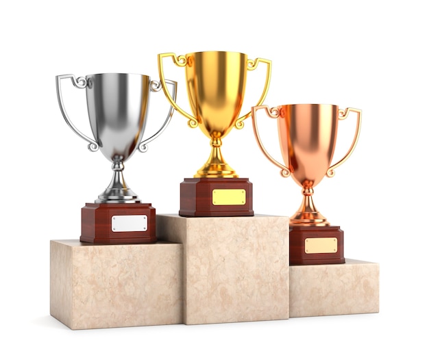 Tres trofeos de copa de premio: copas de trofeo de oro, plata y bronce sobre pedestal de mármol aislado sobre fondo blanco.