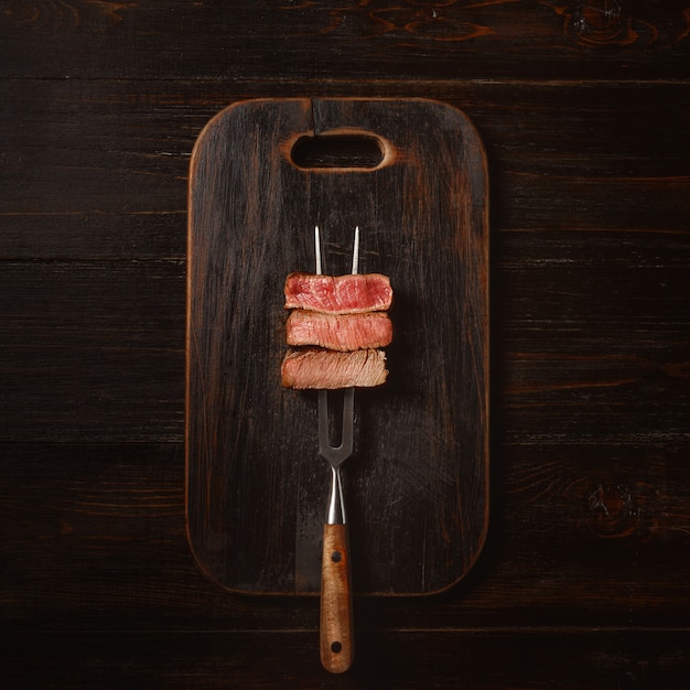 Tres trozos de carne en un tenedor para carne. tres tipos de asado de carne, raro, mediano, bien hecho.