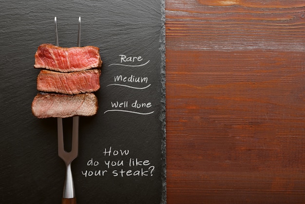 Tres trozos de carne en un tenedor para carne. tres tipos de asado de carne, raro, mediano, bien hecho.