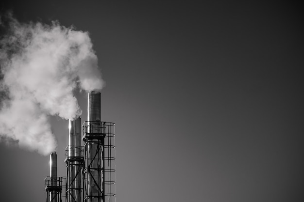 Três tubulações de fumo de uma planta contra o céu. O conceito de poluição ambiental.