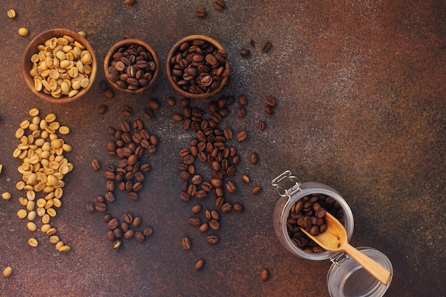 Tres variedades diferentes de granos de café recién tostados en cuencos de madera sobre fondo de piedra oscura