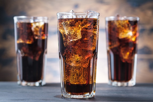 Foto tres vasos de cola con cubitos de hielo y burbujas