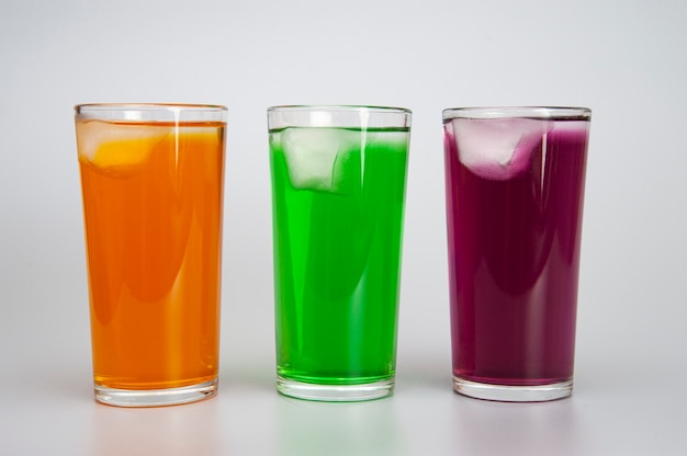 Foto tres vasos con diferentes jugos con hielo.