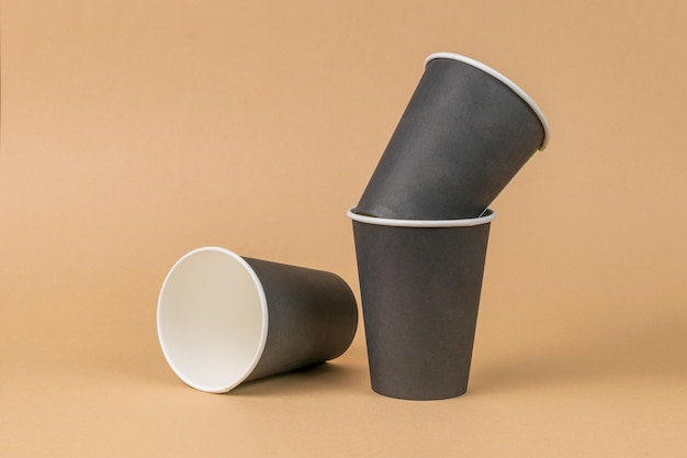Tres vasos de papel oscuro sobre un fondo marrón claro Concepto mínimo