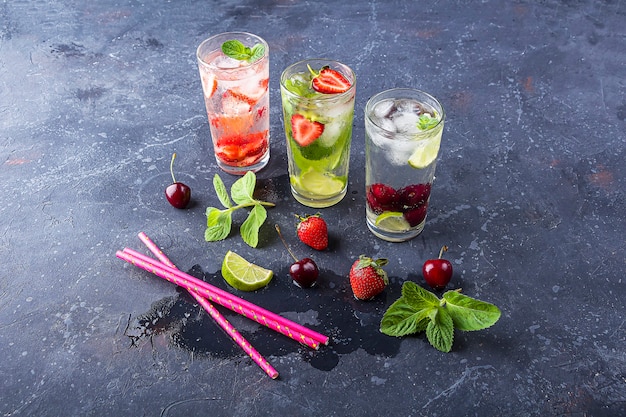 Tres vasos de refrescante bebida de desintoxicación con fresa, lima, cereza y menta