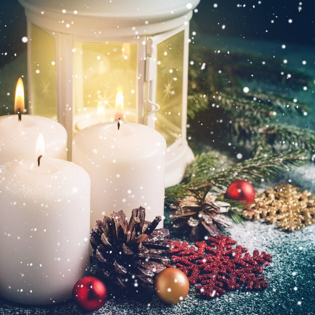 Três velas acesas de Natal e lanterna em fundo turquesa escuro.