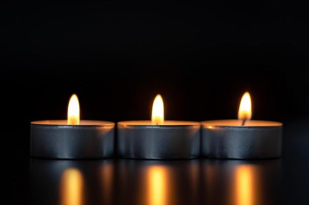 Três velas acesas em um fundo preto