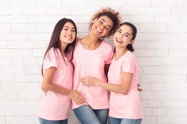 Foto três voluntárias de câncer de mama se abraçam sobre um fundo branco